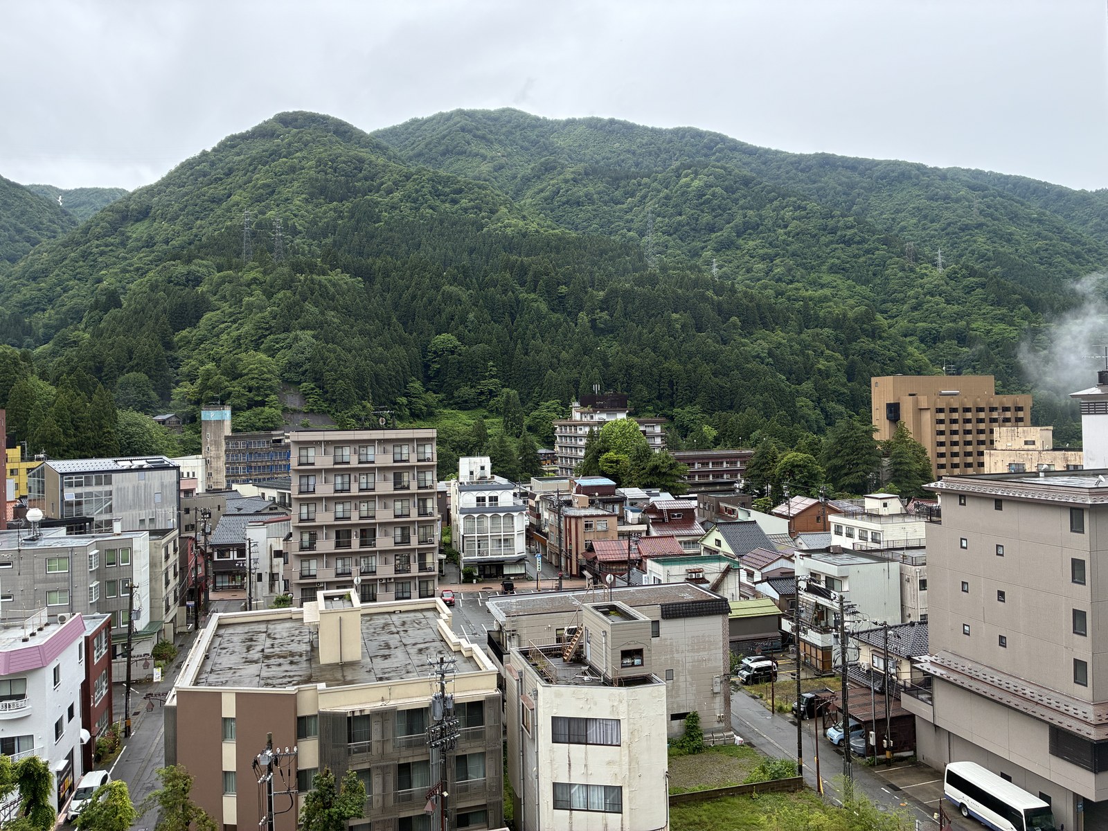 台風の日の朝の宇奈月温泉。路面が濡れて、奥の山から湯けむりが上がっている