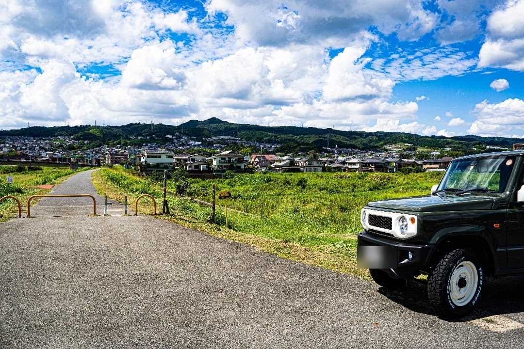 大和川河川敷に停めたジャングルグリーンのジムニーと、遠景の信貴山