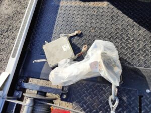 積載車の荷台に置かれたNAロードスターのECUと、錆びた取り付けステー